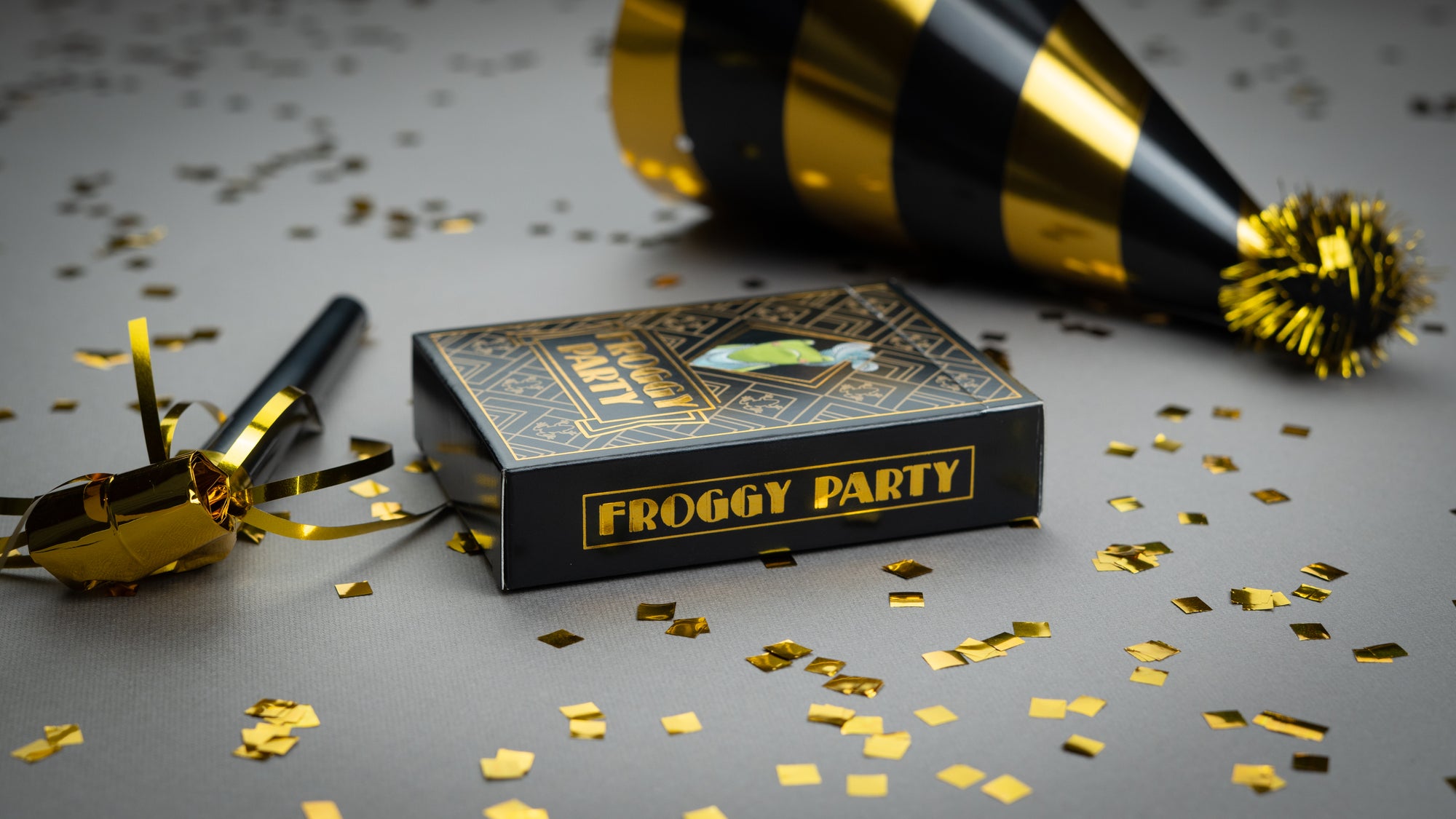 Froggy Party game box with gold confetti and party hat on a gray surface