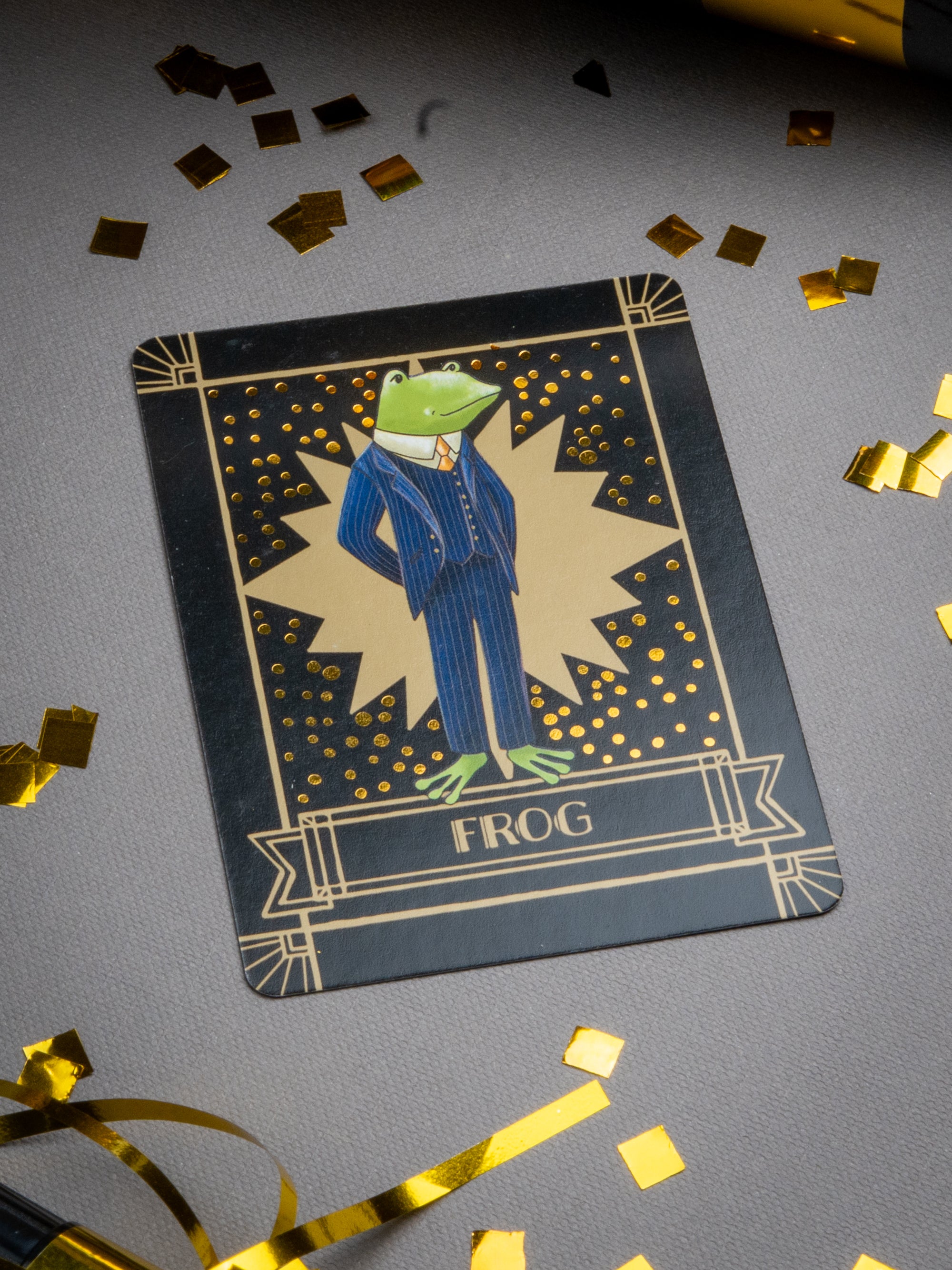 Card with a frog in a suit on a gray background with gold confetti