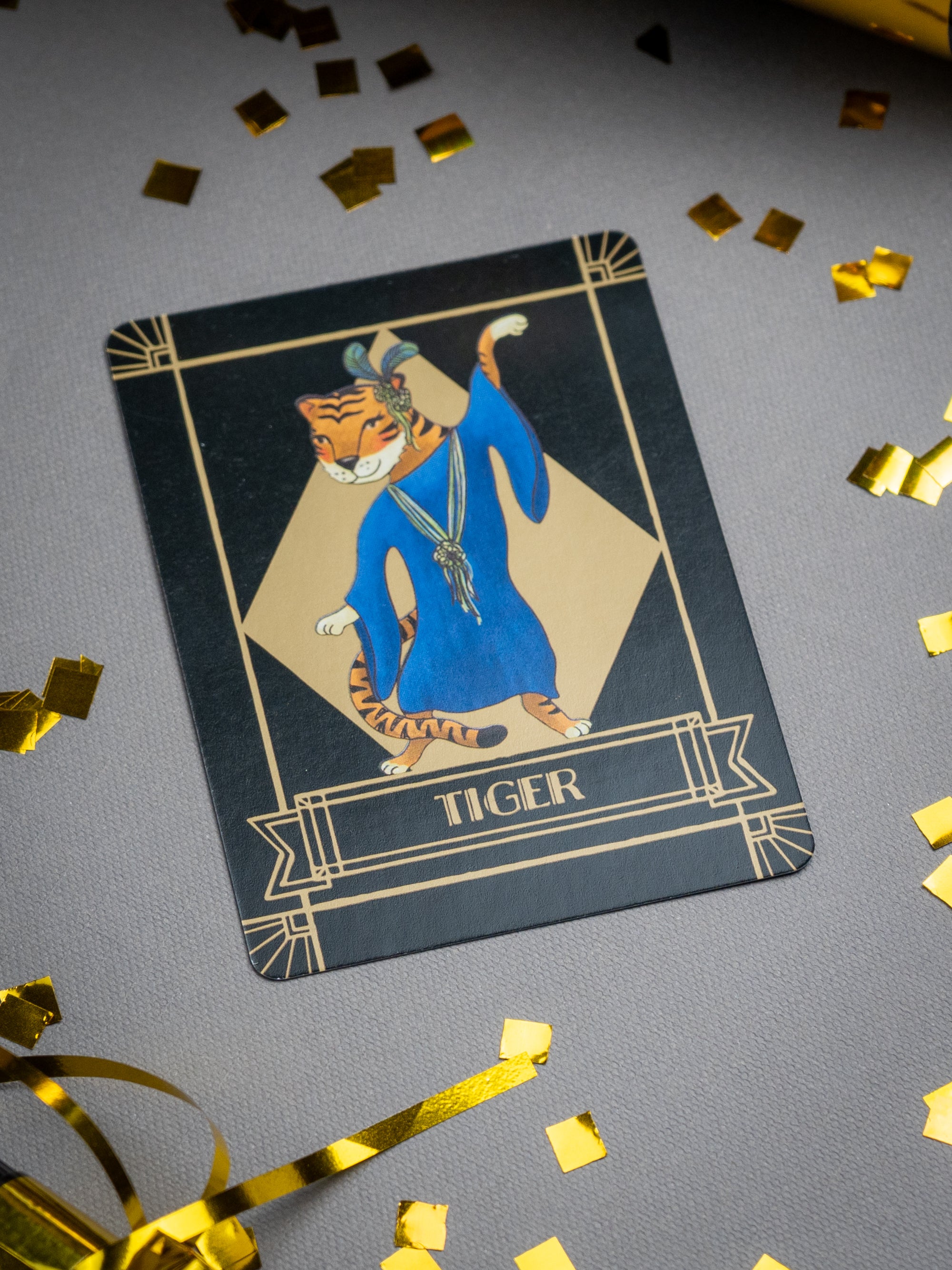 Card featuring a tiger in flowing party attire on a gray background with gold confetti.