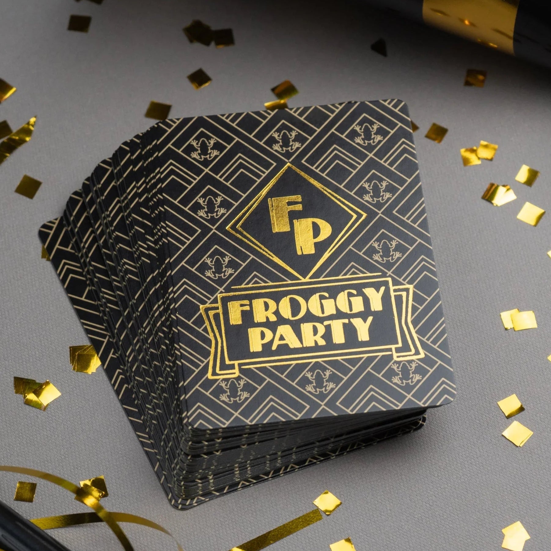 Stack of 'Froggy Party' cards with gold confetti on a gray background