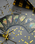 Fanned-out sparkly Frog cards with gold confetti and party hats on a gray background