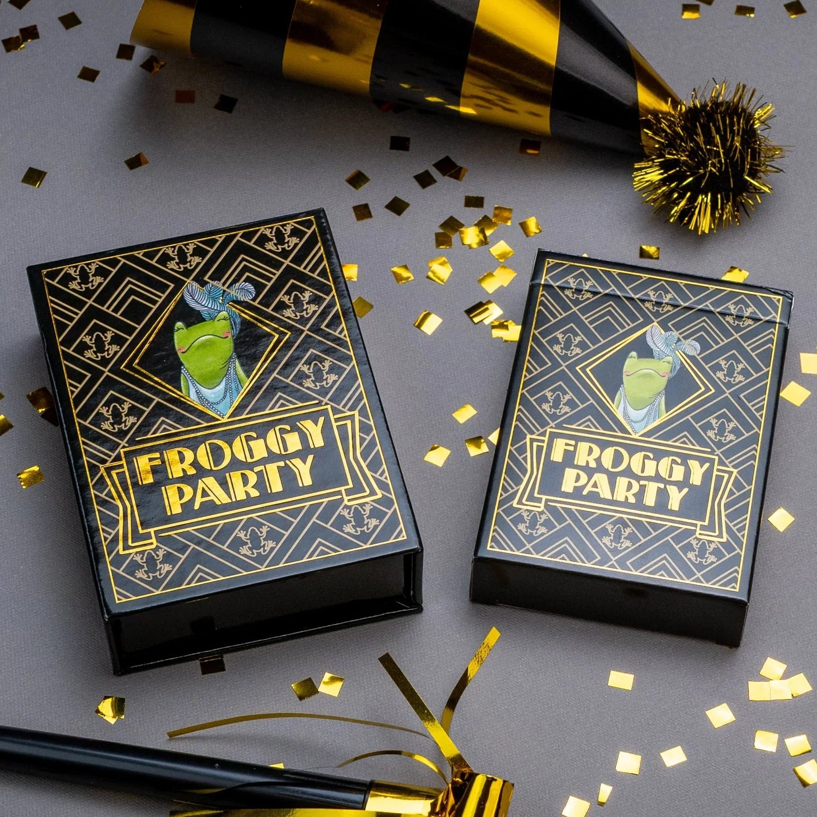 Two 'Froggy Party' game boxes with gold and black party hats and confetti on a gray background.