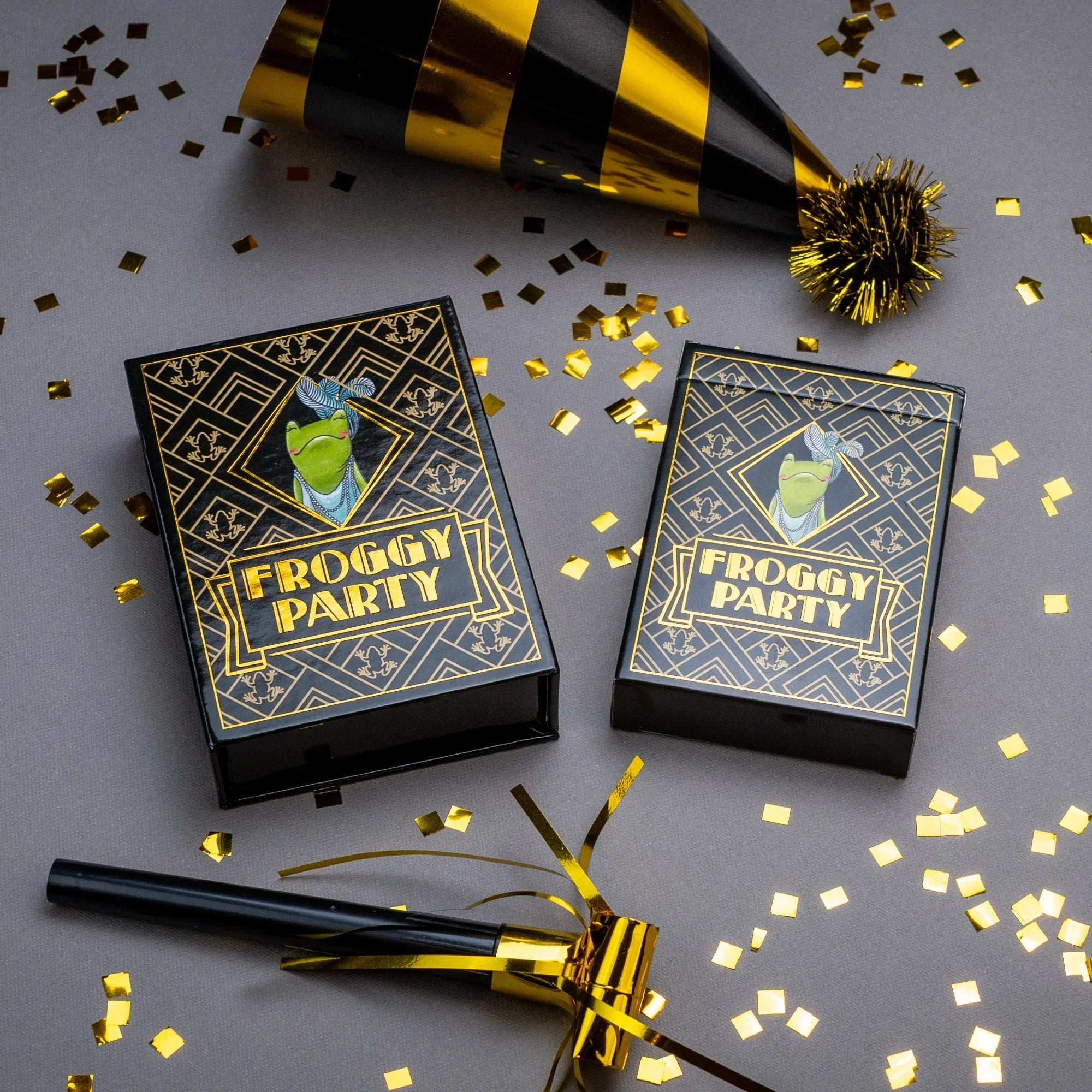Two 'Froggy Party' game boxes with gold and black party hats and confetti on a gray background.