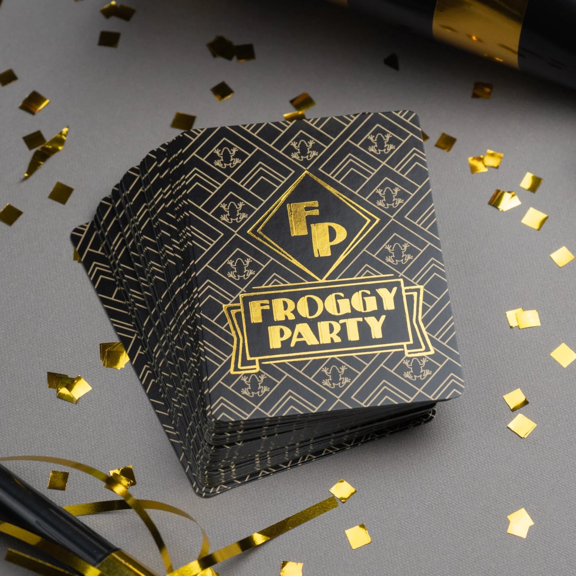 Stack of &#39;Froggy Party&#39; cards with gold confetti on a gray background